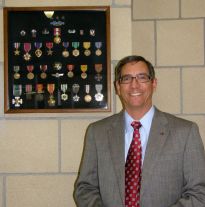 Rick Seitz with hid dads medals at Seitz Elementary